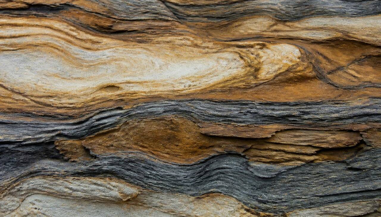Layered sedimentary rock strata in ochre, slate and bone tones